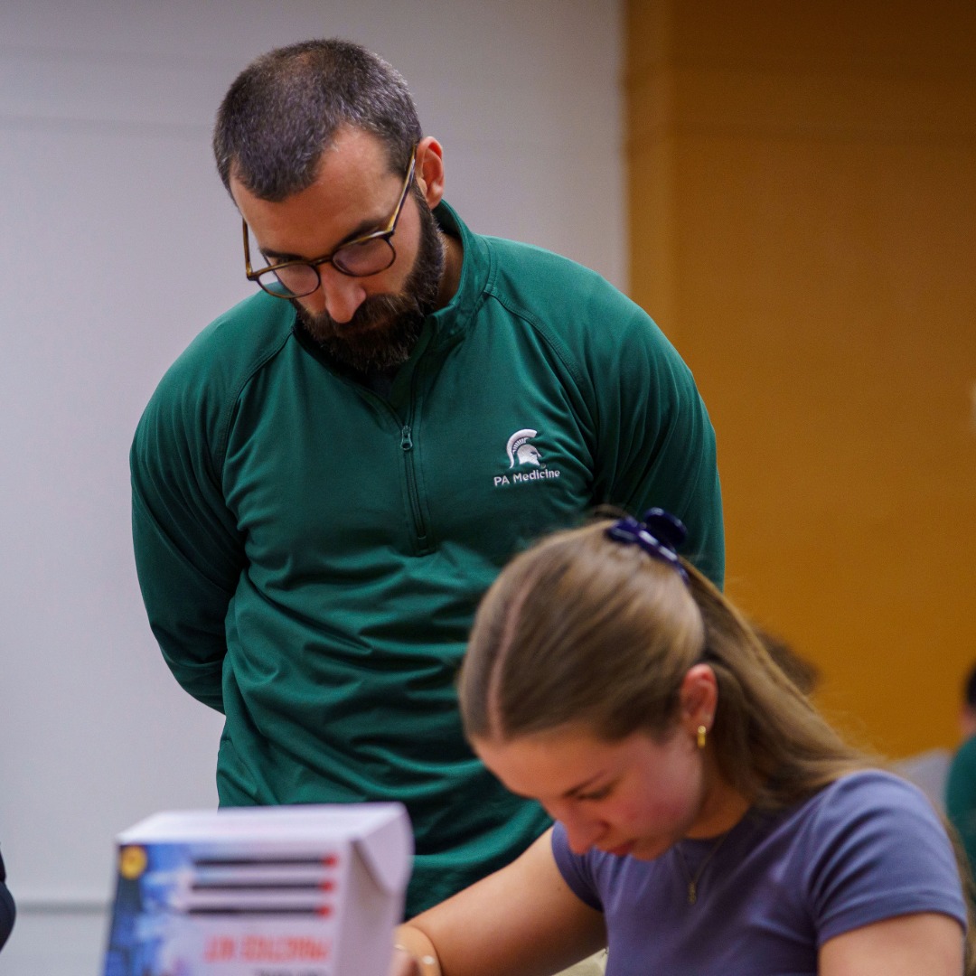 PA program instructor standing behind a student and observing as they practice suturing