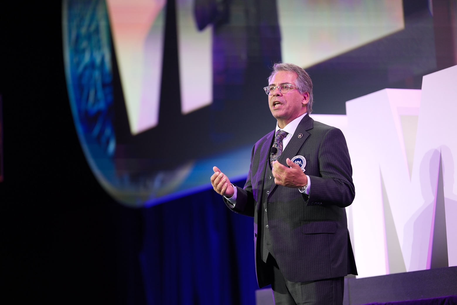 President Piccinini in a suit speaking on stage.
