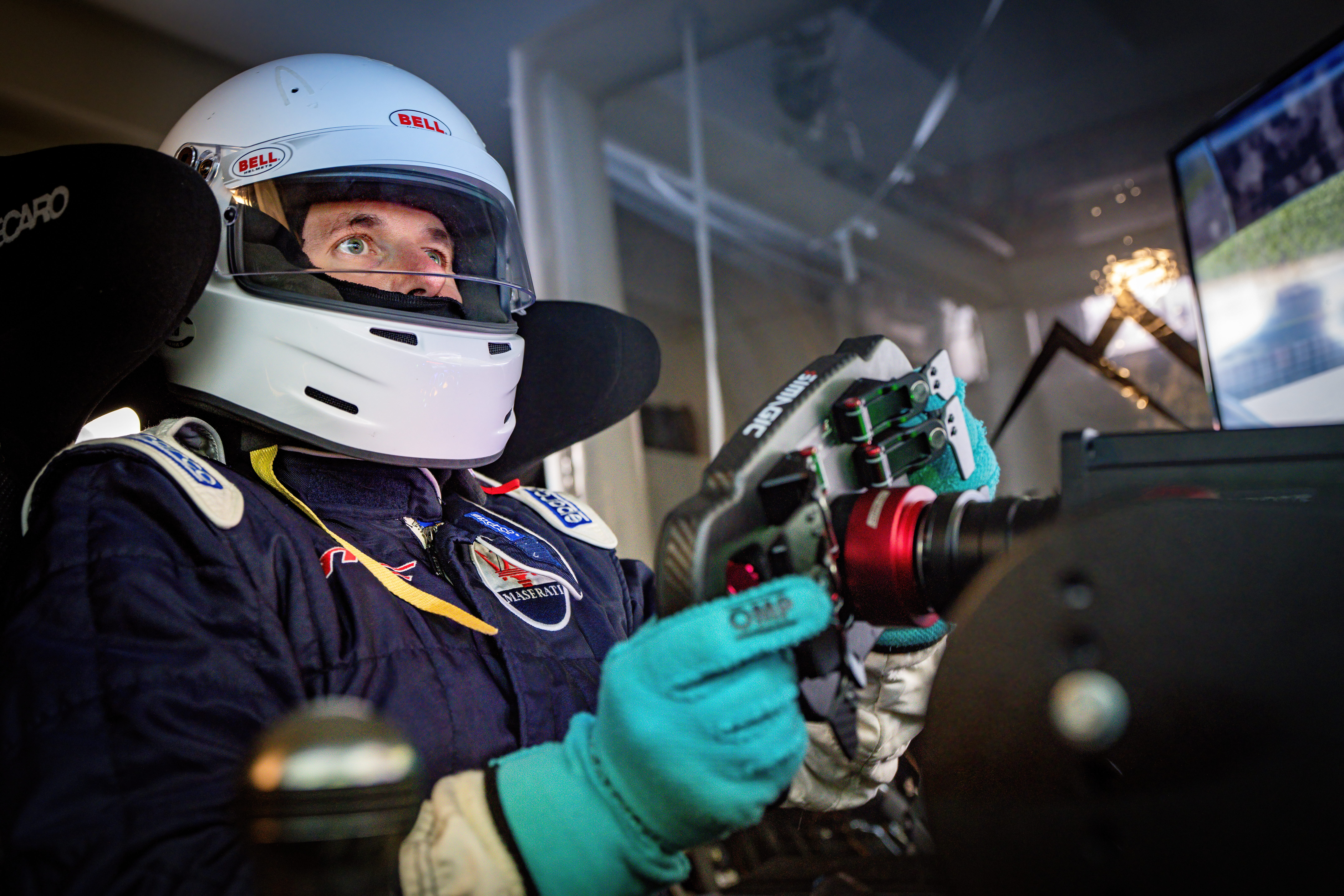 Person in a racing helmet with a steering wheel in a driving simulator.