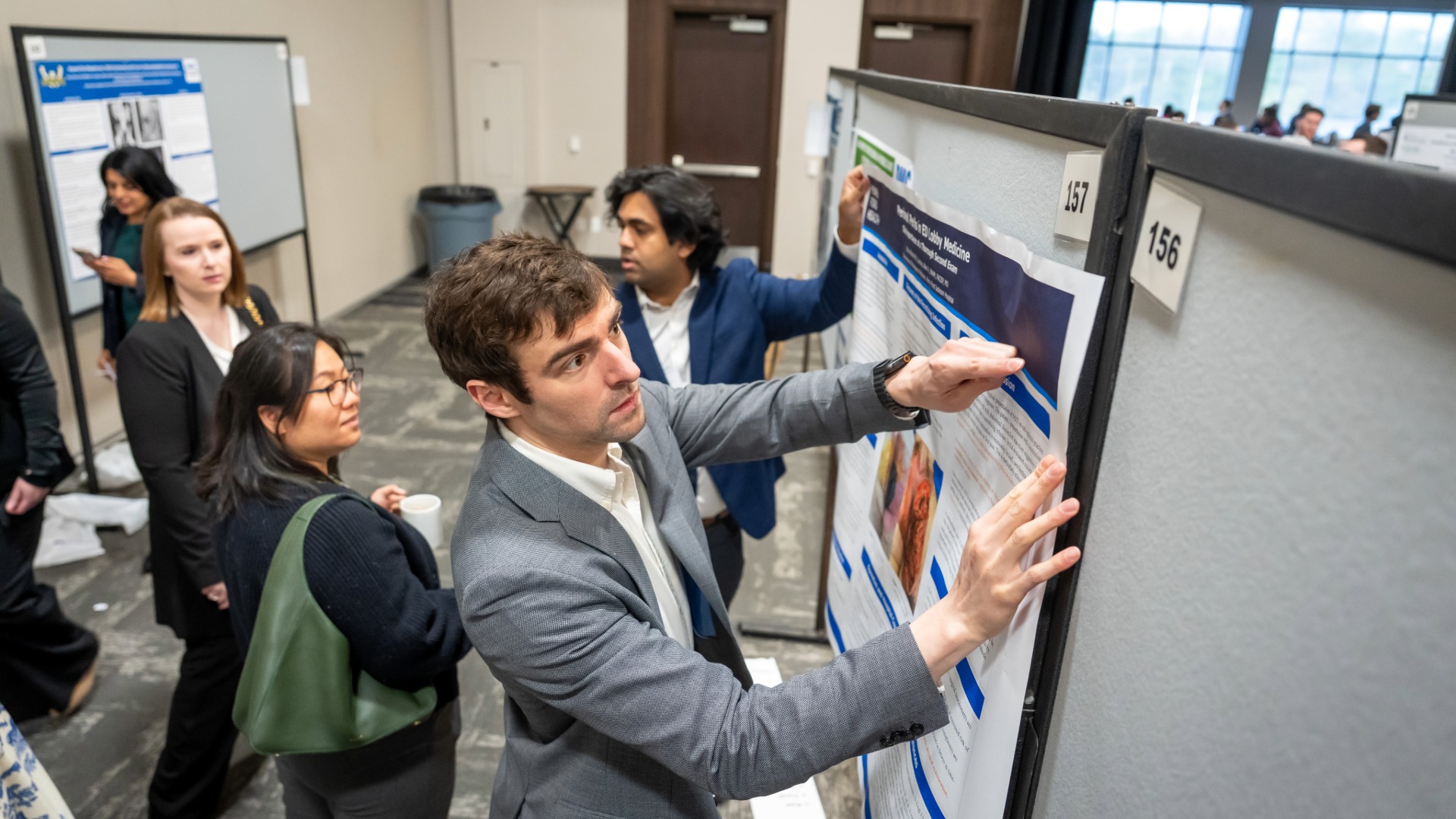 Poster presenter pinning up their poster on a board at the start of research day