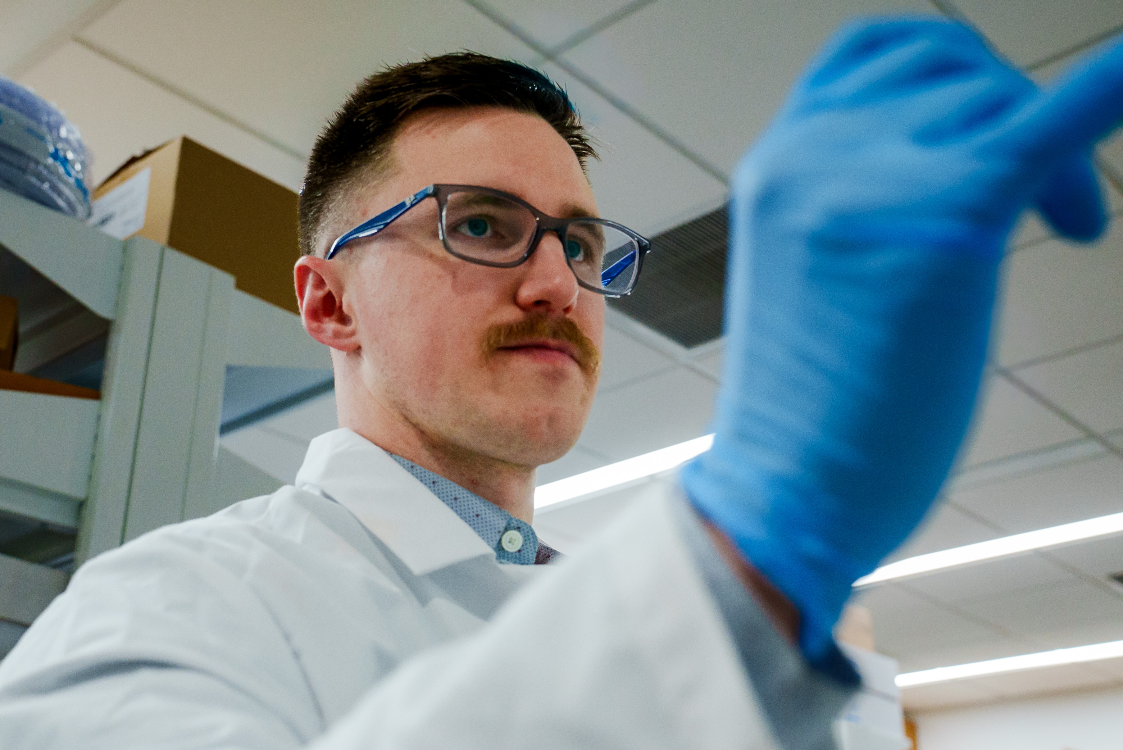 Person in a lab coat and glasses working in a laboratory