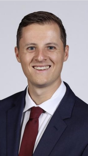 Headshot of Curtiss Johnson smiling in a navy suit with a red tie.