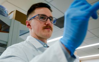 Person in a lab coat and glasses working in a laboratory