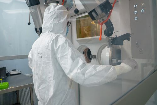 Person in a protective suit working at a sealed chamber in a laboratory