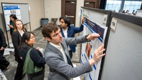 Poster presenter pinning up their poster on a board at the start of research day