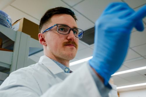 Person in a lab coat and glasses working in a laboratory